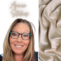 a woman in glasses is smiling and holding a piece of fabric