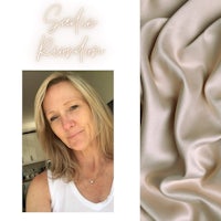 a woman in a white shirt is standing next to a piece of beige silk