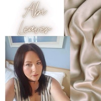 a woman is posing in front of a bed with a bed sheet