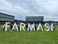 a group of people posing in front of a farmmasi sign