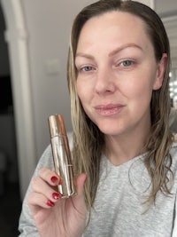 a woman is holding up a bottle of makeup